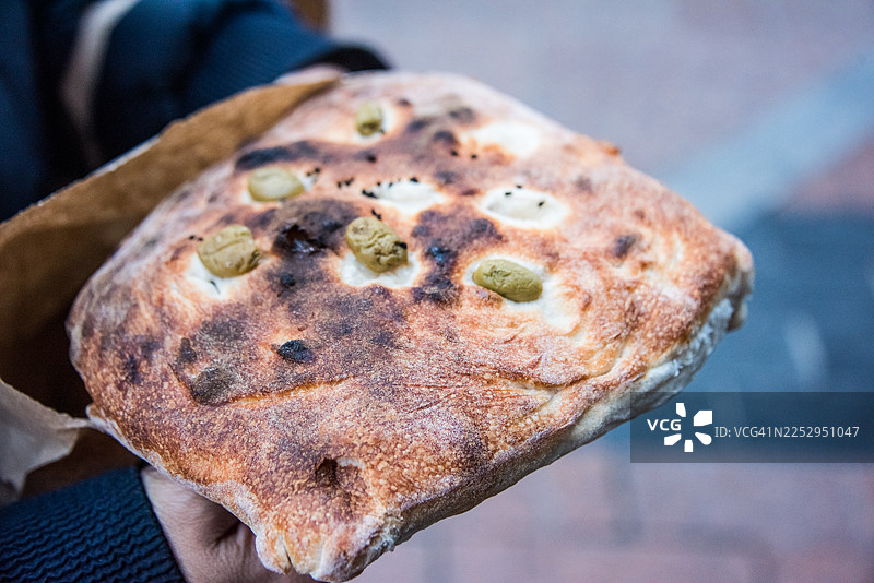 市场上的人们拿着新鲜的橄榄佛卡夏面包图片素材