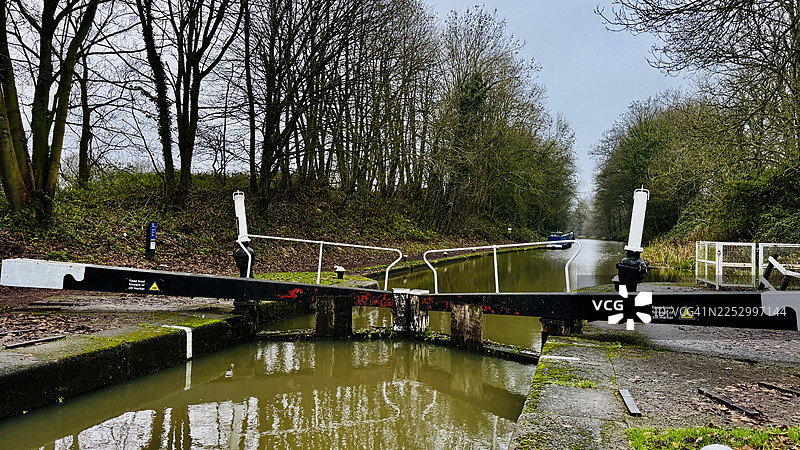 哈顿的顶部船闸，展示了拖曳路径、运河上的步行桥和树木成荫的景象图片素材