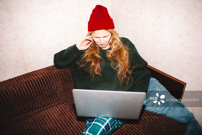 一位年长的女性在家里的沙发上使用笔记本电脑图片素材