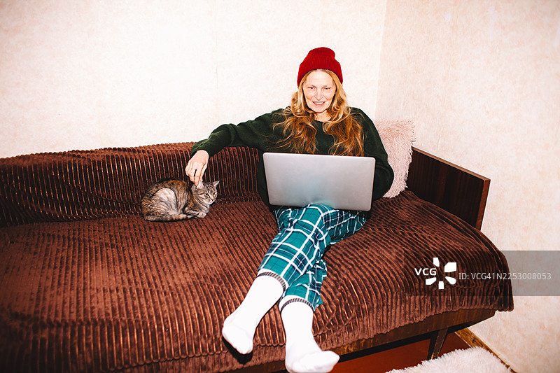 一位年长的女性在家中坐在沙发上使用笔记本电脑图片素材