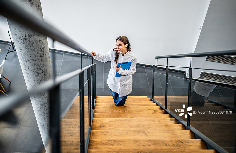 女医生在医院走楼梯，手里拿着病历夹图片素材