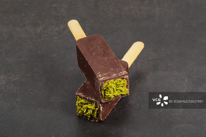 迪拜巧克力糖棒，内填酥脆的 kadaifi 酥皮和开心果酱。带木棍。深灰色背景。特写。图片素材