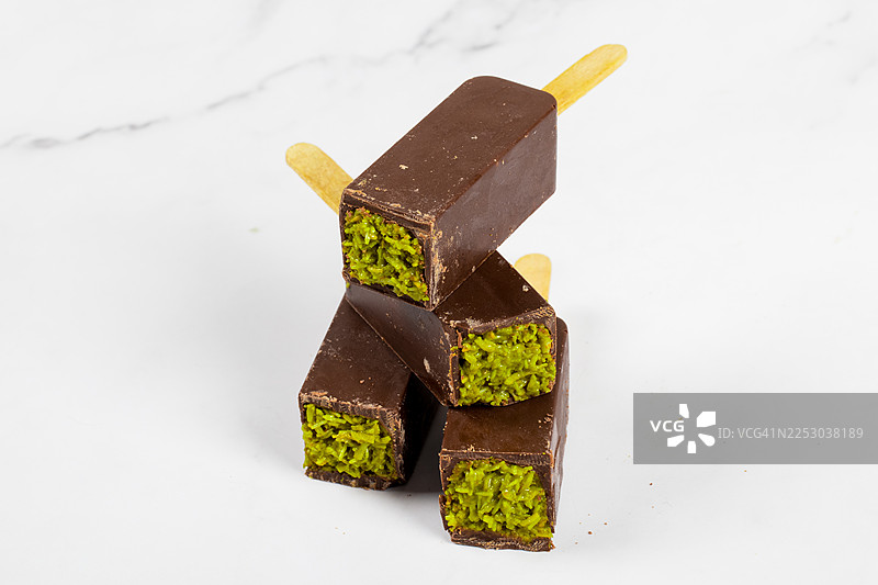 开心果酱馅的纯素迪拜巧克力甜点，包裹着酥脆的Kataifi面团，插在木棍上，特写，白底。图片素材