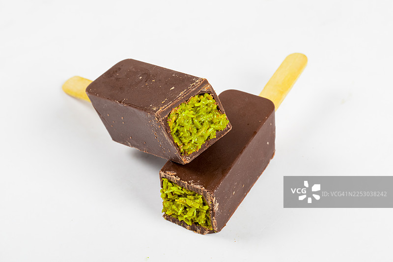 迪拜巧克力甜点，内填酥脆的 kadaifi 面团和开心果酱。插在木棍上。白色背景。特写。图片素材