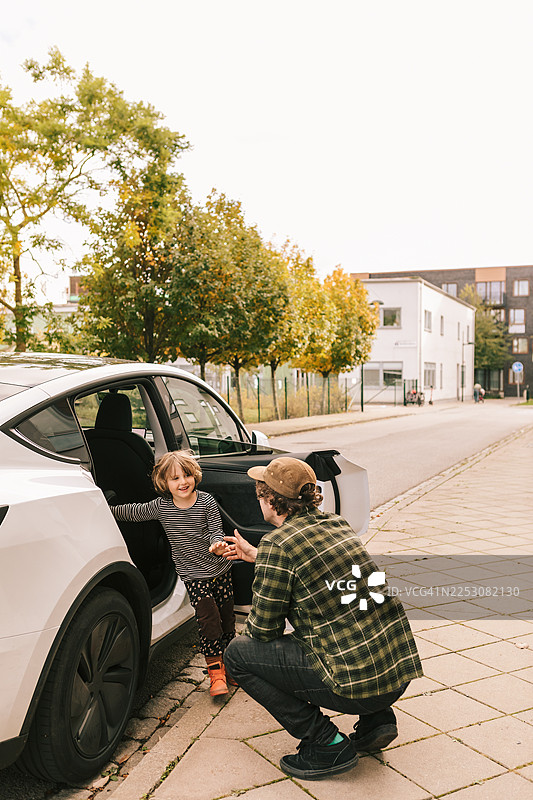 休陪产假的父亲正在帮助儿子下车。图片素材