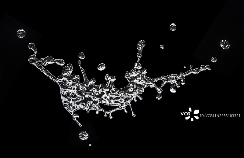 黑色背景上，液态银金属飞溅和滴落的动态画面。图片素材