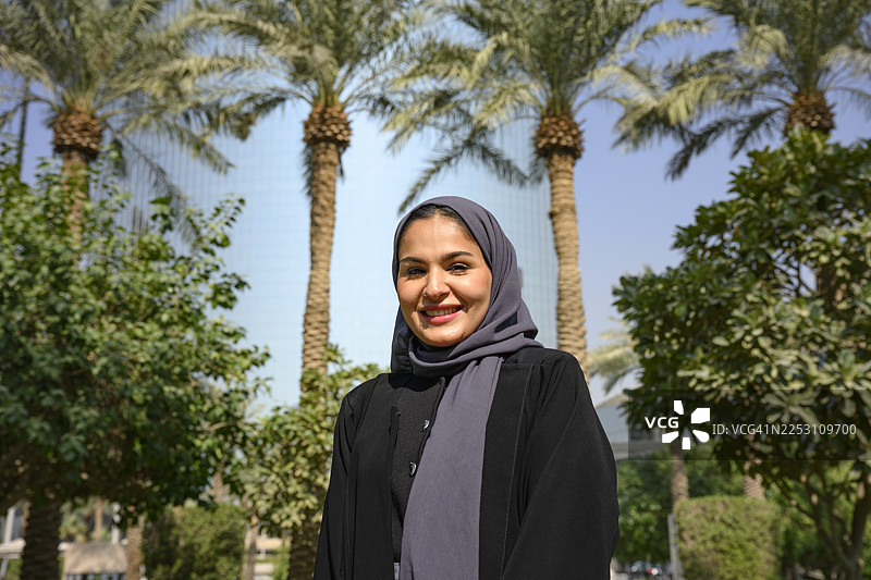 身穿阿巴亚和头巾的阿拉伯女子在户外微笑图片素材