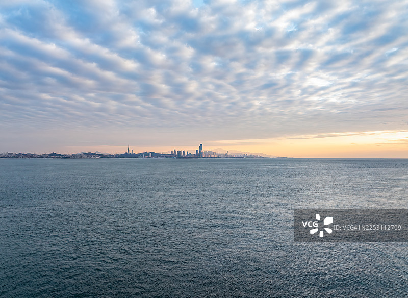 从远处眺望青岛西海岸，城市天际线在卷积高云的映衬下图片素材
