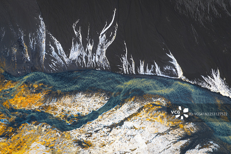 从空中俯瞰，醒目的白色线条划破黑暗，掠过冰岛维克镇（Vik i Myrdal）上方的绿色大地。图片素材