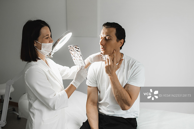 美容诊所咨询，临床医生在环形灯下检查患者的颈部和面部图片素材