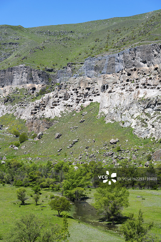 岩石上雕刻着洞穴，周围环绕着绿草和树木，洞穴城镇，洞穴修道院，库拉河，瓦尔季西亚，萨姆茨赫-贾瓦赫蒂州，萨姆茨赫-贾瓦赫蒂，小高加索，格鲁吉亚图片素材