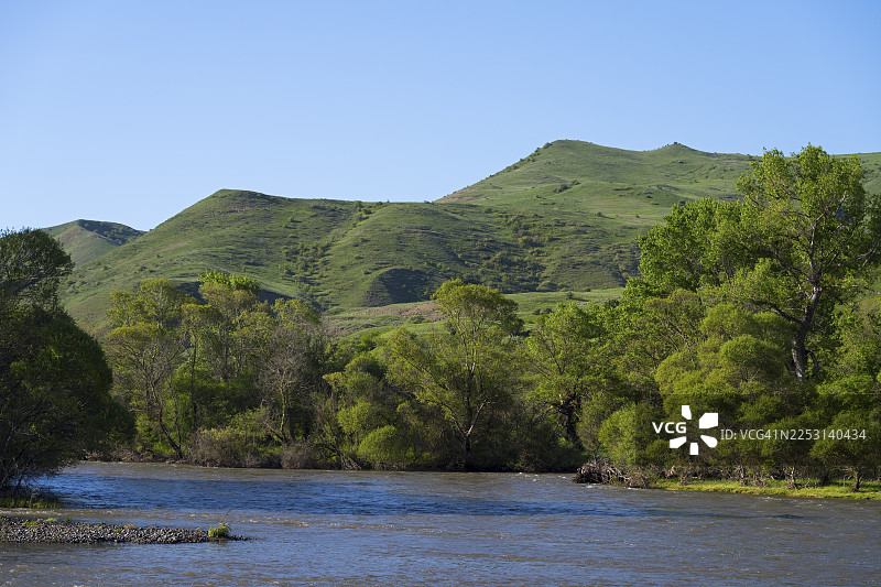 格鲁吉亚萨姆茨赫-贾瓦赫季大区阿斯平扎附近的库拉河，河水环绕着绿色的山丘和树木，天空湛蓝。图片素材