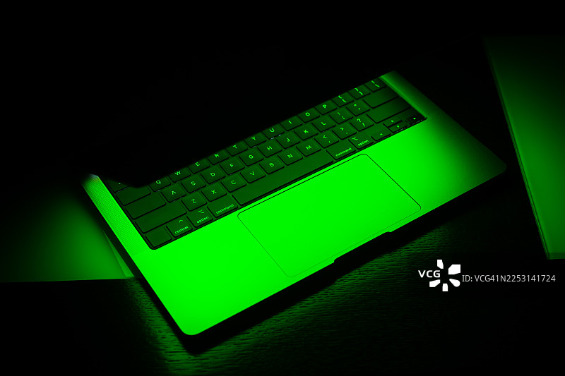 黑色背景上带有绿色霓虹灯光辉的笔记本电脑模型图片素材