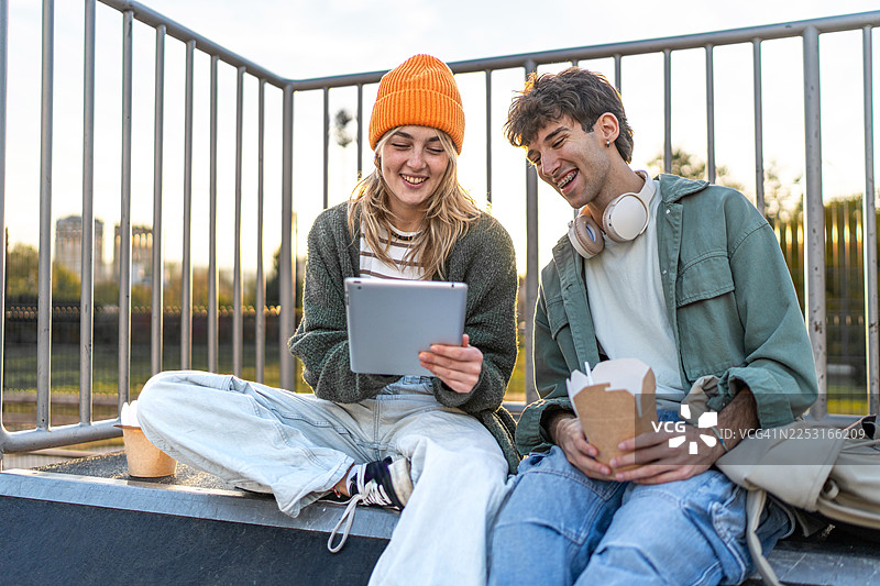 年轻的朋友们在户外分享平板电脑上的数字内容图片素材