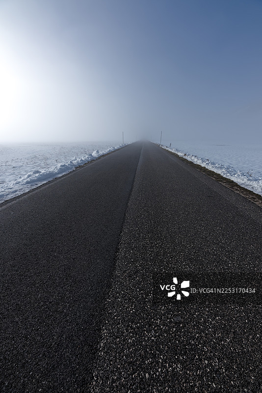 雾气笼罩的雪域高原之间笔直的山路图片素材