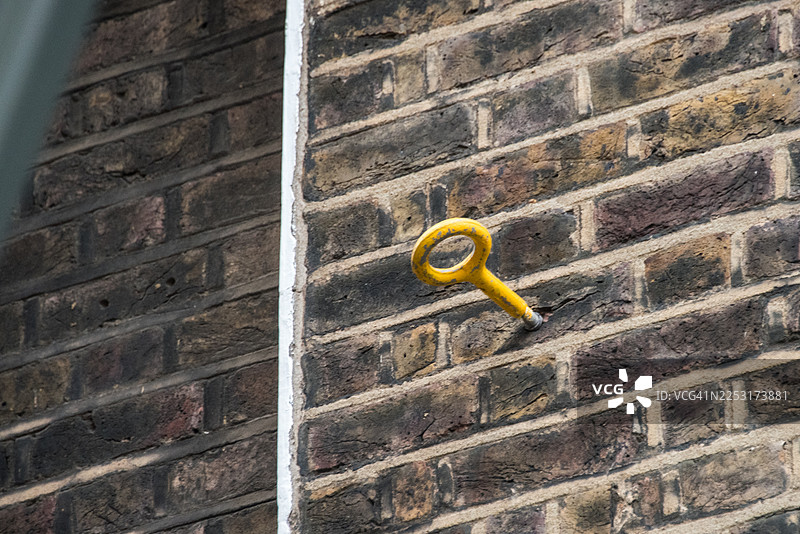 深色砖墙上的黄色金属扣眼图片素材