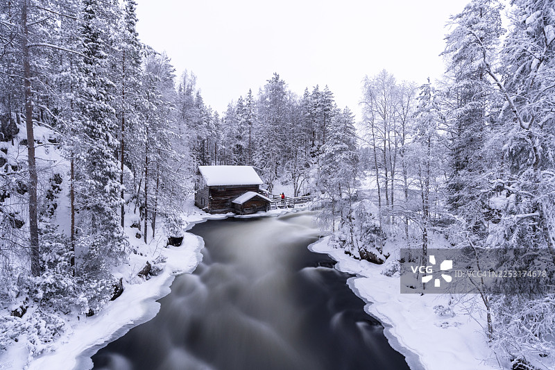 芬兰，白雪覆盖的森林里，老磨坊附近激流中长曝光的水流图片素材