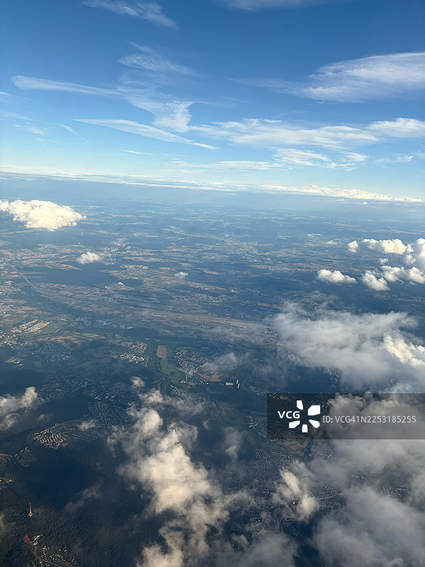 蔚蓝天空下，云朵漂浮在广阔大地之上，令人惊叹的航拍视角捕捉了来自上方的宁静之美。图片素材
