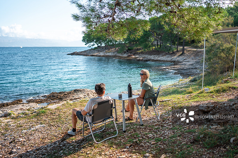 一对成熟的夫妇在风景优美的海岸边露营，享受着早晨的咖啡时光图片素材
