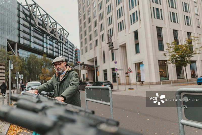 阴天，男子在柏林波茨坦广场探索城市并推着滑板车图片素材