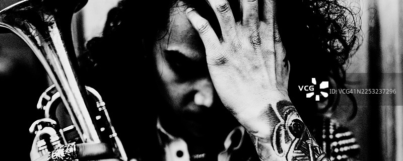黑白亲密肖像：一位年轻的吹小号者在专注与疲惫之间。图片素材