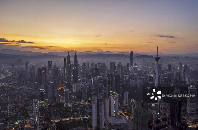 雾气弥漫的吉隆坡天际线日出，伴有朦胧的城市景观和标志性地标图片素材