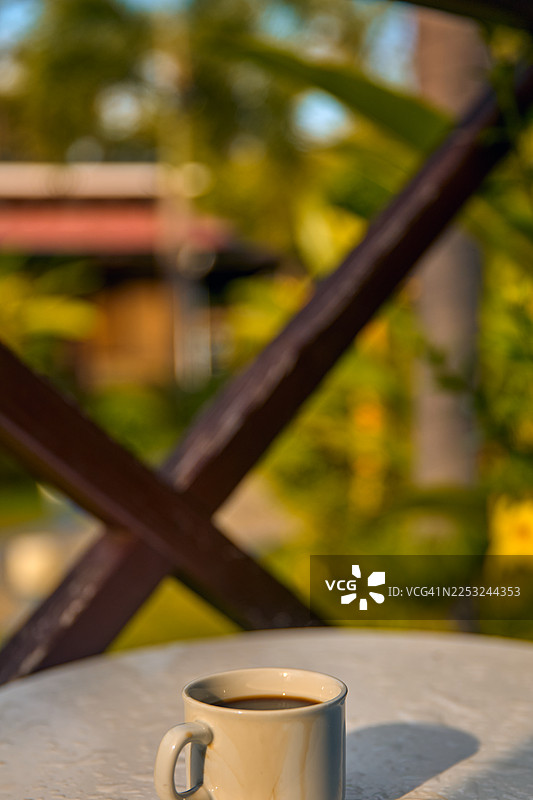 一个浅色的陶瓷咖啡杯在石桌上投下影子。图片素材