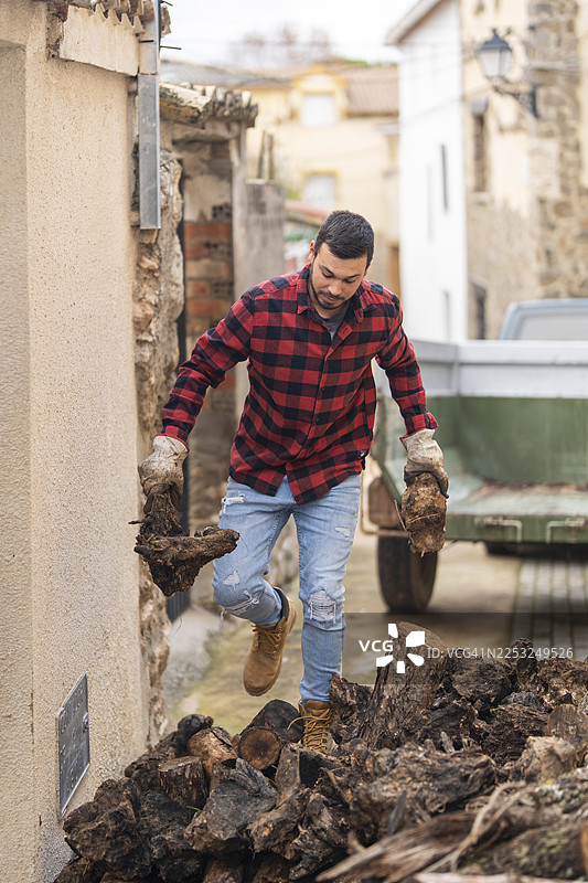 一名成年男子正在处理木块，准备堆放图片素材