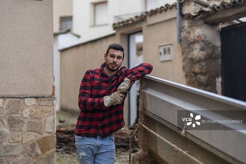 戴着工作手套的年轻男子倚靠在卡车旁图片素材