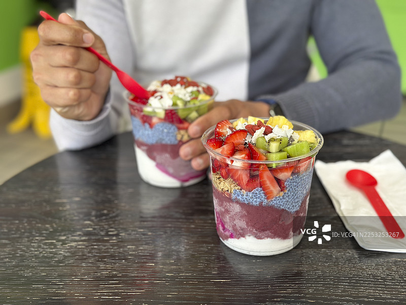 透明杯中的巴西莓碗，配有新鲜水果、奇亚籽和格兰诺拉麦片图片素材