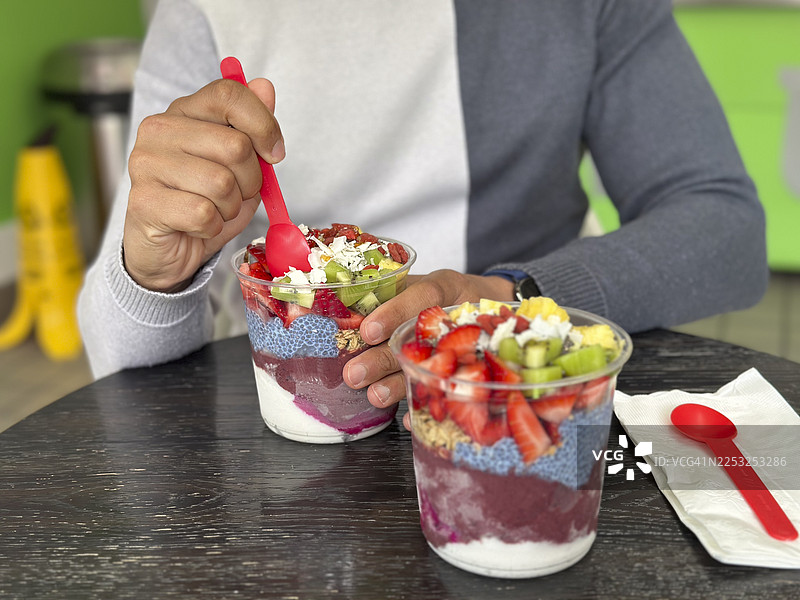 透明杯中的巴西莓碗，配有新鲜水果、奇亚籽和格兰诺拉麦片图片素材