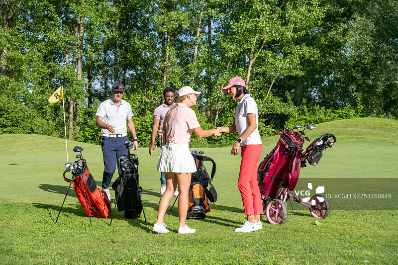 不同肤色的高尔夫球手在绿茵场上分享欢乐时光图片素材
