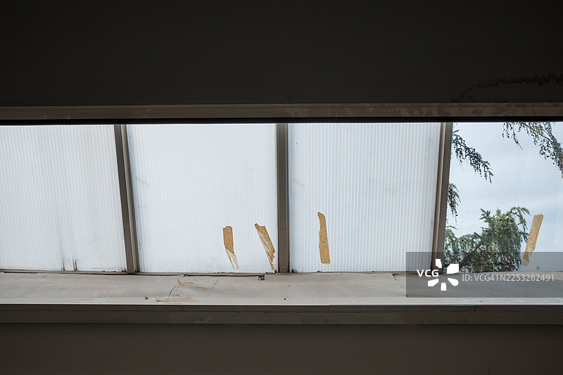 布满灰尘的半透明窗户面板，上面贴着剥落的胶带条图片素材