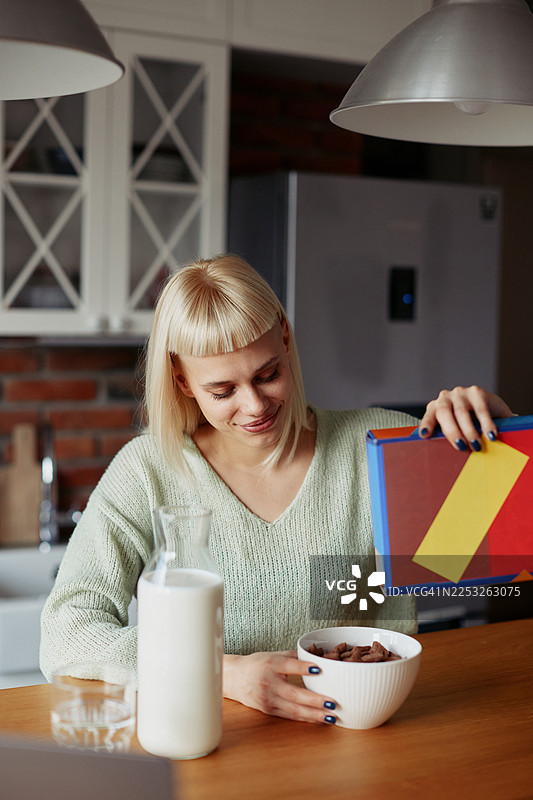 年轻的时尚女性在家中享用早餐麦片和新鲜水果的晨间日常图片素材