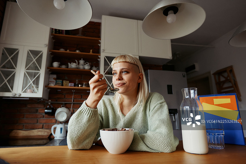 年轻的时尚女性在家办公期间，在现代厨房享用早餐，生活休闲图片素材