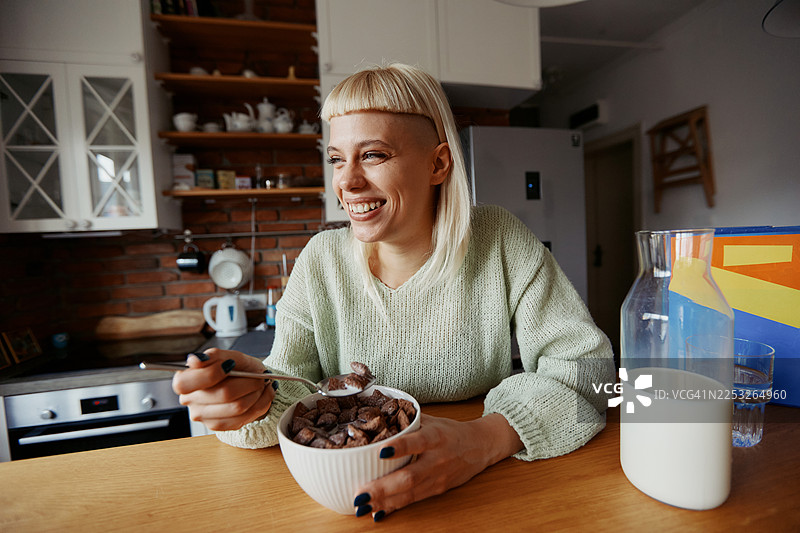 年轻的时尚女性在家工作时，在现代厨房享用早餐图片素材