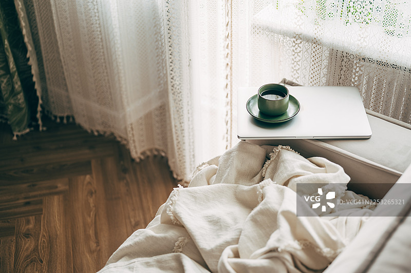 一个打开的笔记本电脑放在木桌上，旁边还有一个带碟子的咖啡杯图片素材