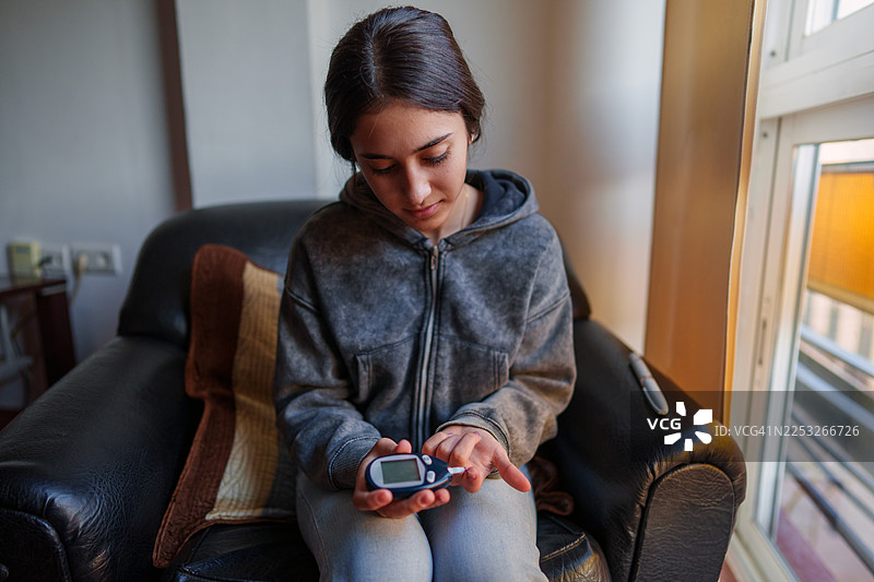 年轻女子用血糖仪检查血糖水平图片素材