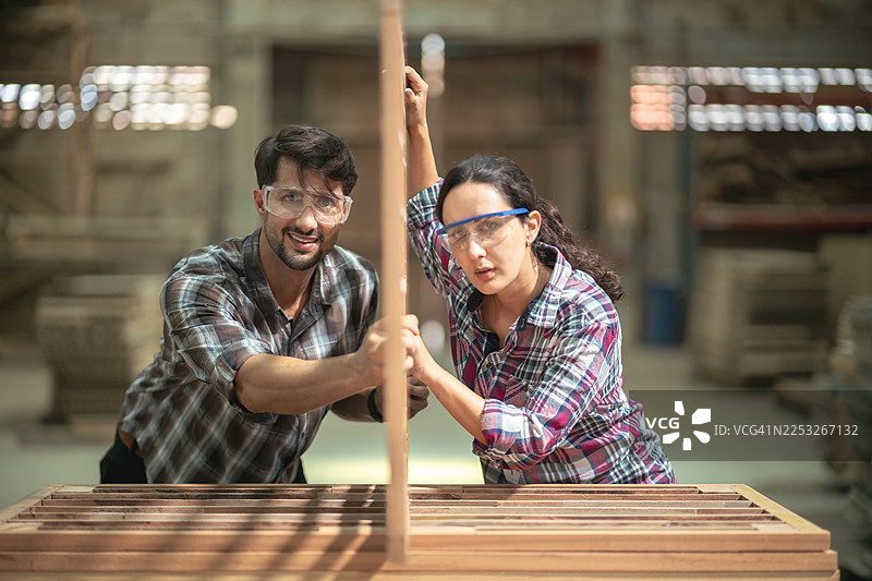 两位工匠在工厂里检查木板并评估材料质量。图片素材