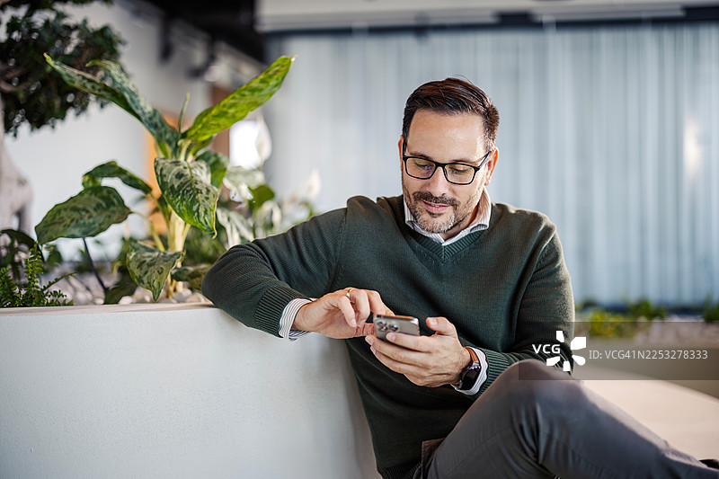 男人在现代办公室休息区使用智能手机图片素材