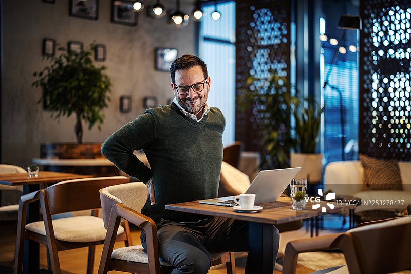 男人在咖啡馆远程工作时感到背痛图片素材
