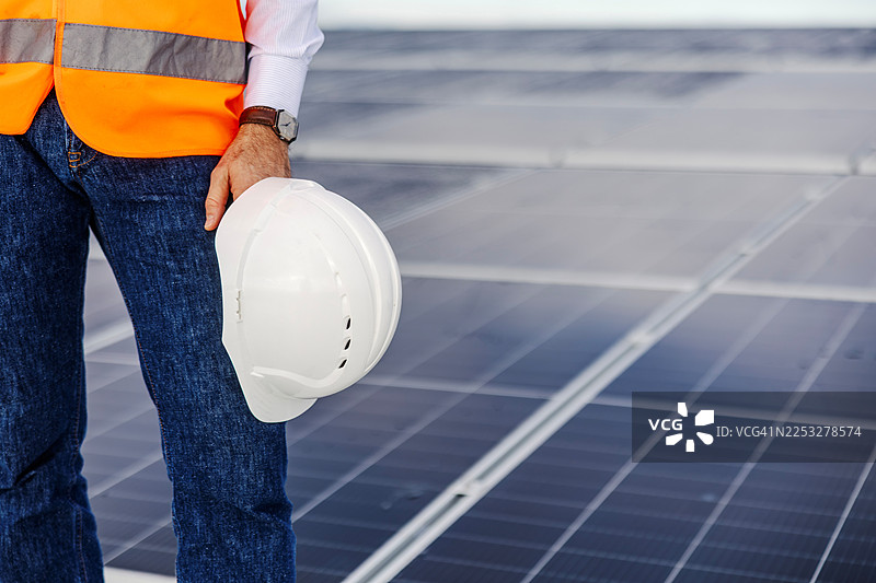 工人头戴安全帽站在太阳能电池板屋顶上图片素材