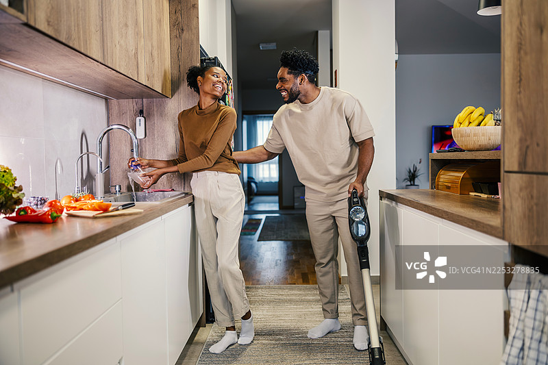 快乐的夫妇在厨房里打扫卫生并准备新鲜蔬菜图片素材