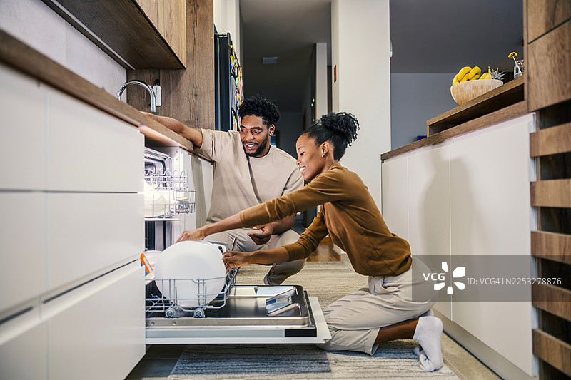 快乐的夫妇在现代厨房里装洗碗机图片素材