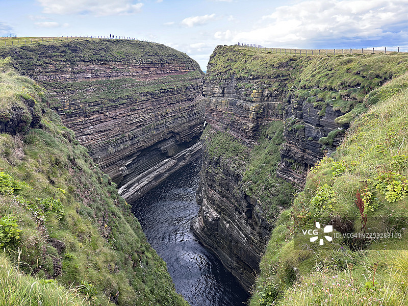 苏格兰约翰 o'格罗茨邓肯斯比岩石间的深邃峡谷，两侧是陡峭的悬崖，覆盖着绿草图片素材