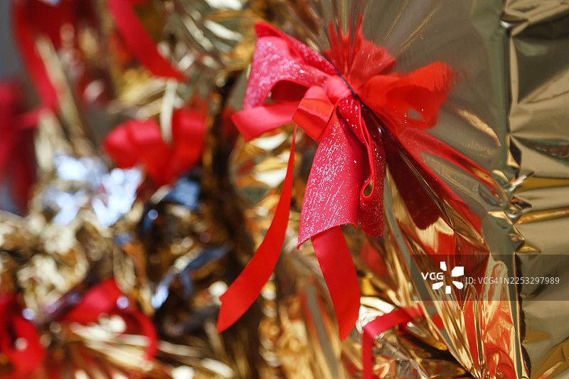 堆满全画幅的金色礼品盒，饰有红色蝴蝶结和丝带图片素材