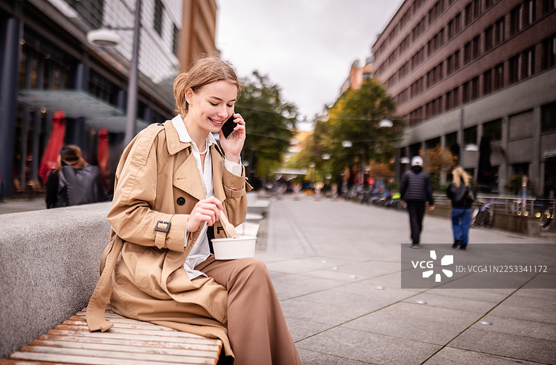 在生机勃勃的柏林波茨坦广场都市环境中，一边用餐一边接听电话图片素材