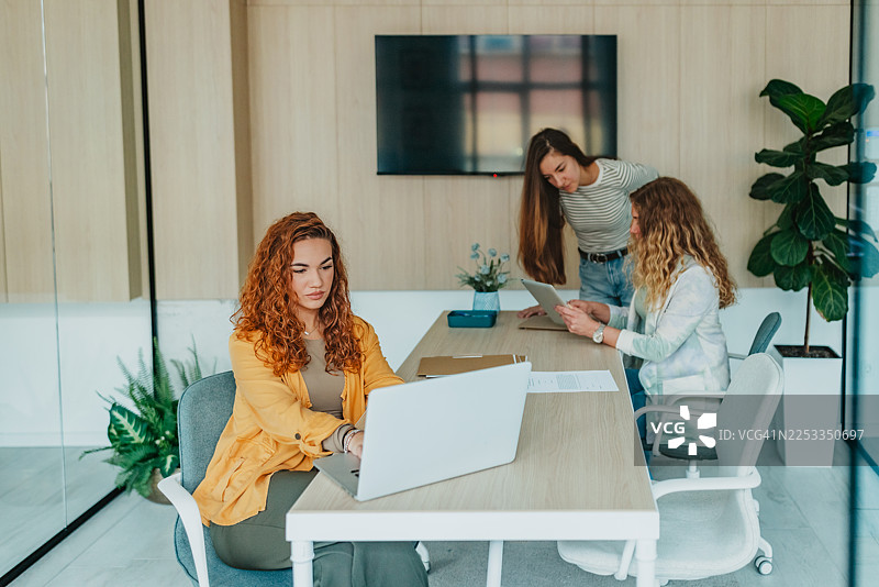 一群同事在工作时间内于现代办公室空间内进行工作和讨论图片素材