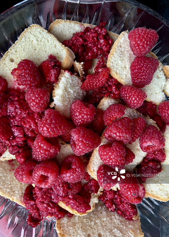 第一部分 - 准备树莓松糕，将手指饼干切半放入碗中，然后加入树莓。图片素材
