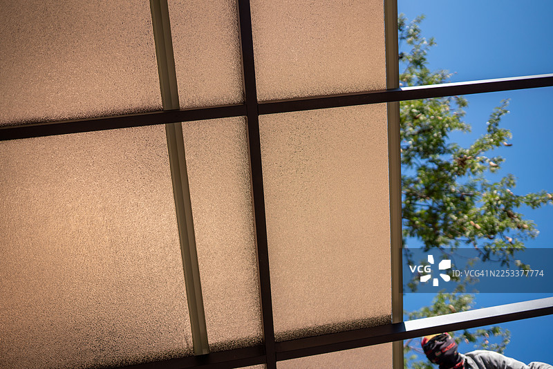 玻璃屋顶下的户外工作场所维护照片，晴朗天空，仰角拍摄，体力劳动，聚焦图片素材